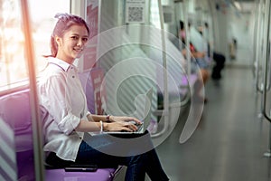 Asian young woman using a notebook on the sky train, leisure and daily life