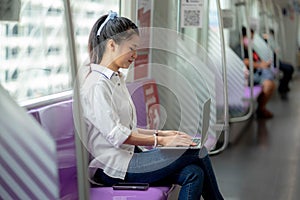 Asian young woman using a notebook on the sky train, leisure and daily life