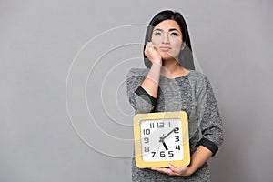 Asian young woman waiting and holding big clock