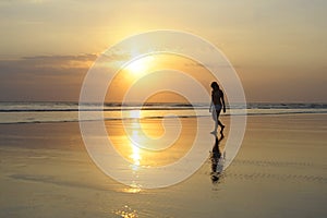 Asian young woman walking peacefully on desert beach on sunset in meditation and freedom concept