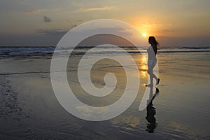 Asian young woman walking peacefully on desert beach on sunset in meditation and freedom concept