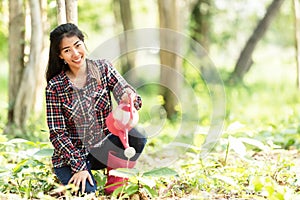 Asian young woman water the plant and sapling tree outdoors in nature spring for reduce global warming growth