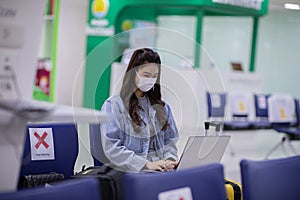 Asian young woman wearing face maks holding passport and boarding pass at airport Due Covid-19 flu virus pandemic