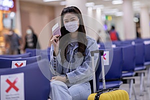 Asian young woman wearing face maks holding passport and boarding pass at airport Due Covid-19 flu virus pandemic photo