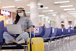 Asian young woman wearing face maks using laptop computer at airport Due Covid-19 flu virus pandemic photo