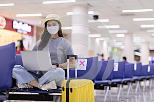 Asian young woman wearing face maks using laptop computer at airport photo