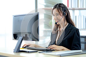 Asian young woman working in call centre. Young friendly operator woman agent with headsets working in a call centre