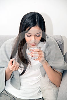 Asian young woman wrapped in a blanket and during illness and taking antipyretics.