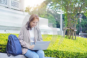 Asian young woman or young student sitting with laptop outdoors,