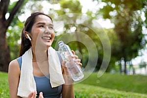 Asian young women drink water from a plastic bottle after exercises or sports. Asian woman running in garden. Beautiful fitness