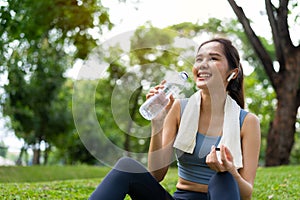 Asian young women drink water from a plastic bottle after exercises or sports. Asian woman running in garden. Beautiful fitness
