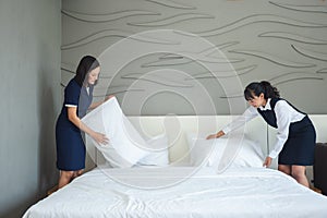 Asian young woman room maid making bed and pillow in hotel.