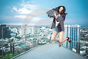 Asian young women surf skate or skates board outdoors on beautiful summer day. Happy young women play surf skate ans jump at roof