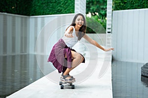 Asian young women surf skate or skates board outdoors on beautiful summer day. Happy young women play surf skate at park