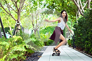 Asian young women surf skate or skates board outdoors on beautiful summer day. Happy young women play surf skate at park