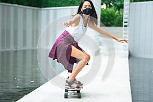 Asian young women surf skate or skates board outdoors on beautiful summer day. Happy young women play surf skate at park