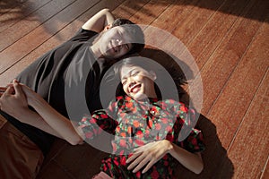 Asian younger man and woman lying on wood floor with happiness face