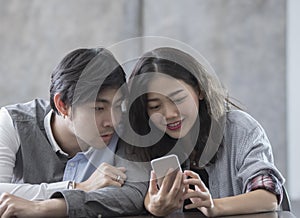 Asian younger man and woman watching on smart phone with happy f