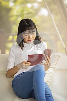 Asian younger woman ralaxing reading a book