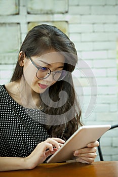 Asian younger woman reading message on computer tablet