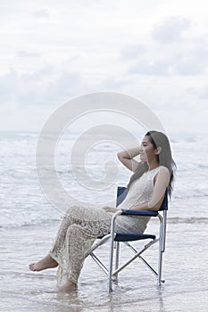asian younger woman sitting on relaxing chair on sea beach vacation time