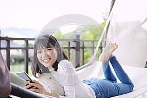 Asian younger woman toothy smiling with happiness holding smart phone in hand ,relaxing lifestyle