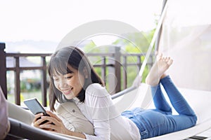 Asian younger woman toothy smiling with happiness holding smart phone in hand ,relaxing lifestyle