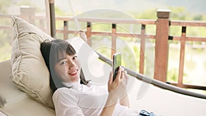 Asian younger woman toothy smiling with happiness holding smart phone in hand ,relaxing lifestyle