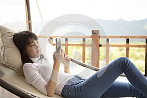 Asian younger woman toothy smiling with happiness holding smart phone in hand ,relaxing lifestyle