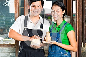 Asians with handmade pottery in clay studio