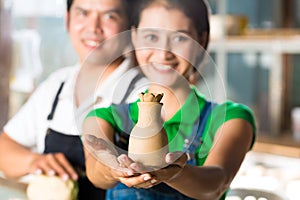 Asians with handmade pottery in clay studio