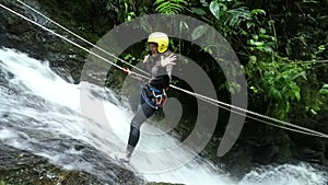 Asiatic Girl Rappelling A Waterfall In Ecuadorian Rainforest