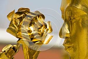 Flower adorning a majestic statue featuring a man's visage photo