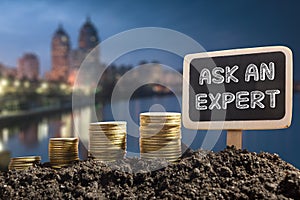 Ask an expert. Financial opportunity concept. Golden coins in soil Chalkboard on blurred urban background