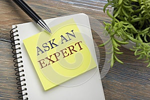 Ask an expert. Notepad with message, pen, reminder and flower. Office supplies on desk table top view.