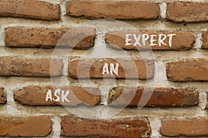 Ask an expert symbol. Concept words Ask an expert on white paper on brick wall. Beautiful brick wall background. Business and ask