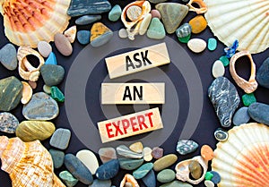 Ask an expert symbol. Concept words Ask an expert on wooden blocks on a beautiful black table black background. Sea shell and