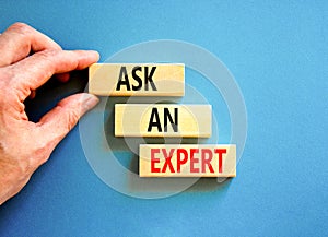 Ask an expert symbol. Concept words Ask an expert on wooden blocks on a beautiful blue table blue background. Businessman hand.