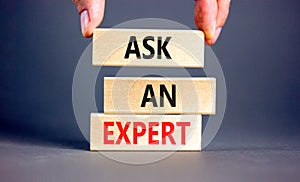 Ask an expert symbol. Concept words Ask an expert on wooden blocks on a beautiful grey table grey background. Businessman hand.