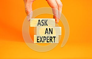 Ask an expert symbol. Concept words Ask an expert on wooden blocks on a beautiful orange table orange background. Businessman hand