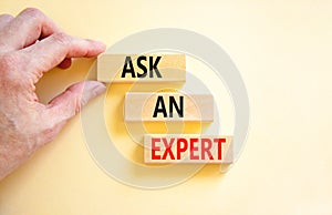 Ask an expert symbol. Concept words Ask an expert on wooden blocks on a beautiful white table white background. Businessman hand.