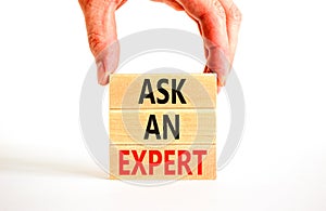 Ask an expert symbol. Concept words Ask an expert on wooden blocks on a beautiful white table white background. Businessman hand.