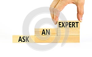Ask an expert symbol. Concept words Ask an expert on wooden blocks on a beautiful white table white background. Businessman hand.