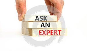 Ask an expert symbol. Concept words Ask an expert on wooden blocks on a beautiful white table white background. Businessman hand.