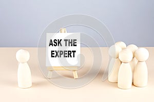 ASK THE EXPERT text on easel with wooden figure, meeting concept