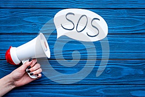 Ask for help concept. Megaphone near cloud with word SOS on blue wooden background top view copy space