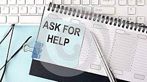 ASK FOR HELP text on blue sticker on planning and keyboard,blue background