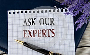 ASK OUR EXPERTS - words on a white sheet with a black notepad and pen