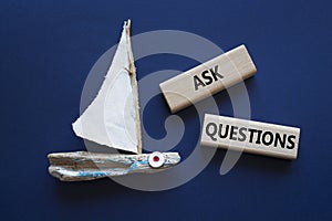 Ask Questions symbol. Wooden blocks with words Ask Questions. Beautiful deep blue background with boat. Business and Ask Questions