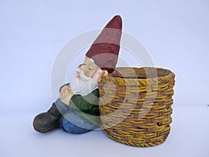 Sleeping garden gnome, sitting, leans against a basket. on white background